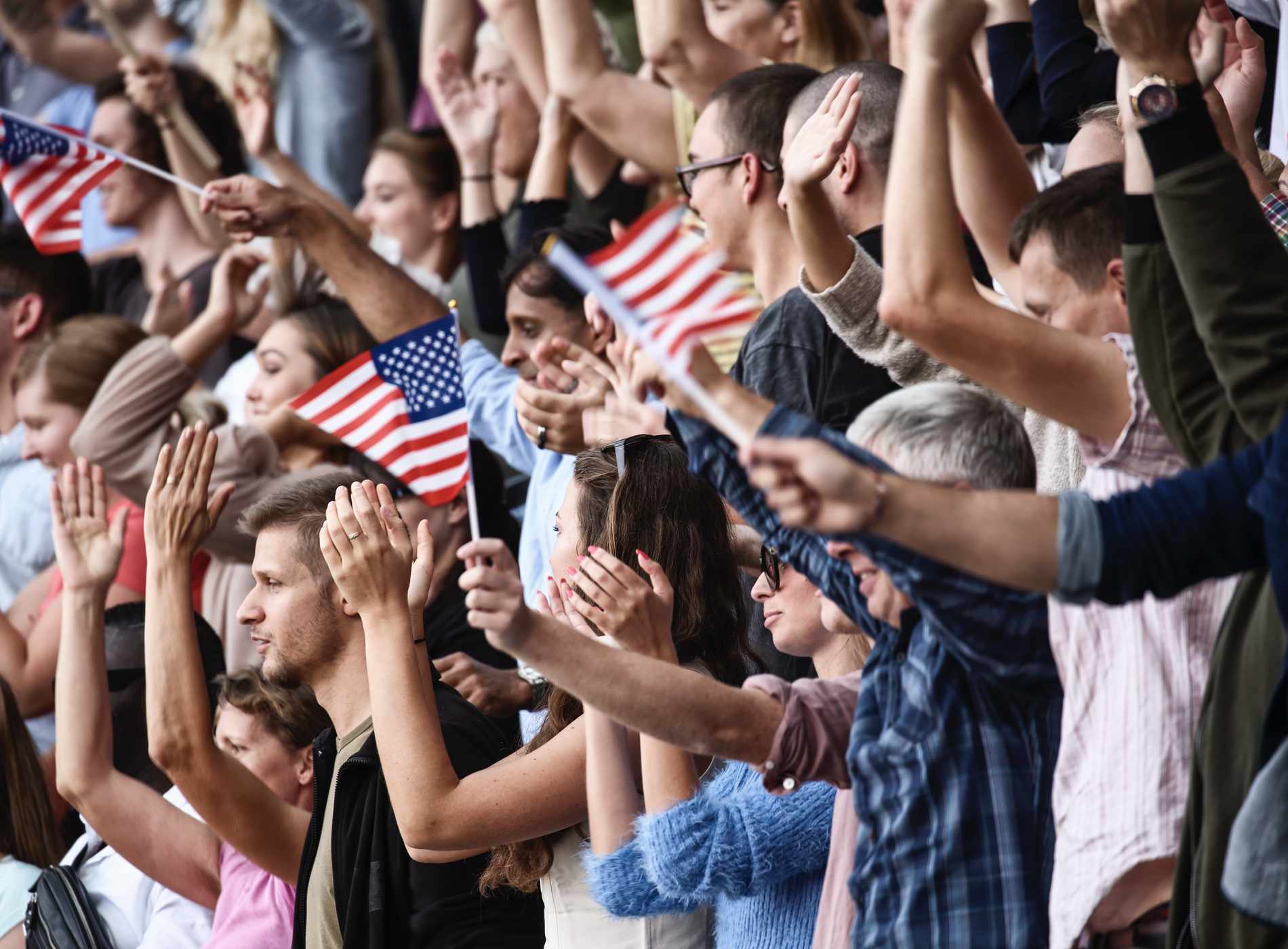 USA colored flags waving above large crowd on a stadium.