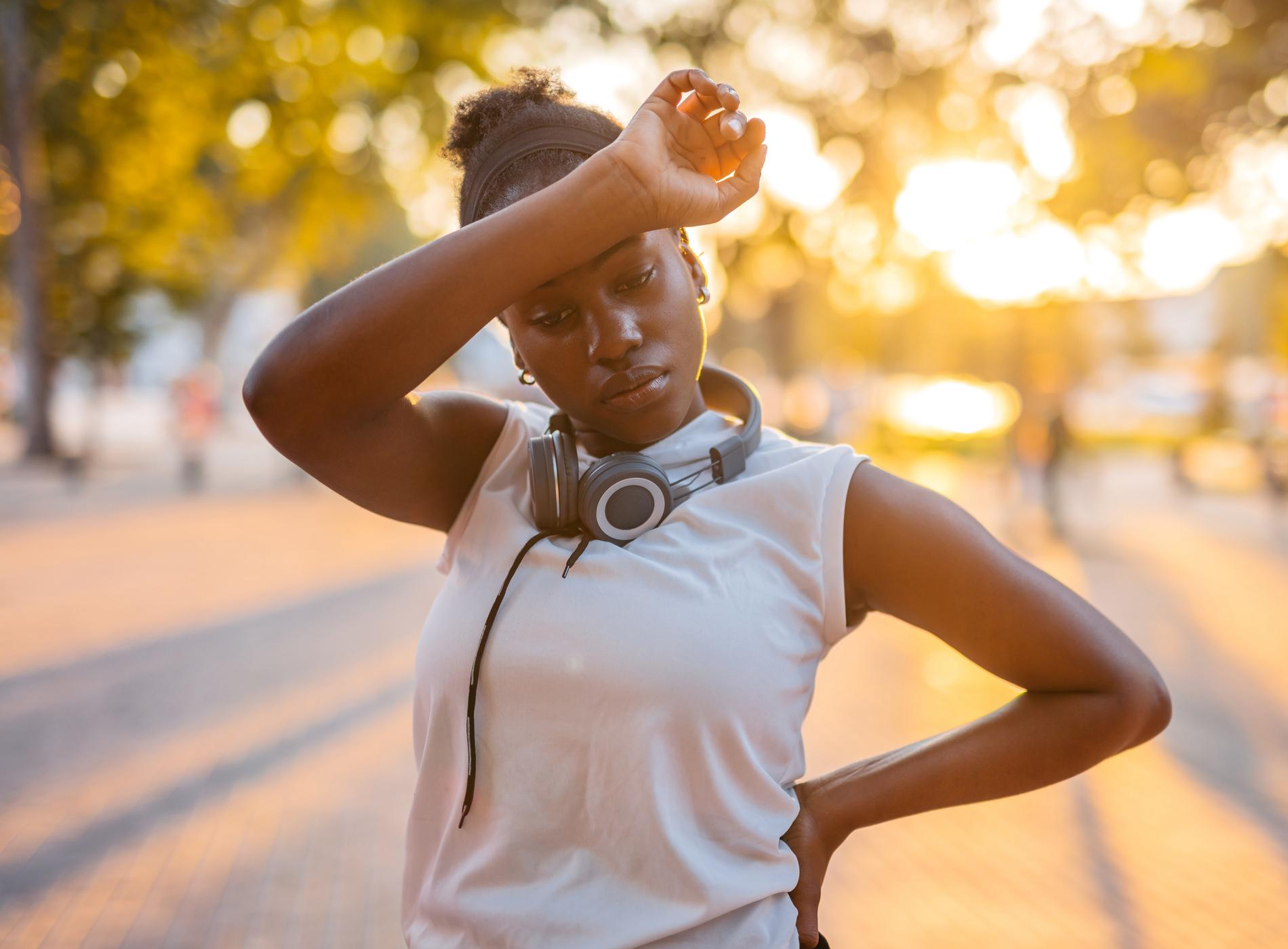 Beautiful young black woman exhausted after jogging in the park.