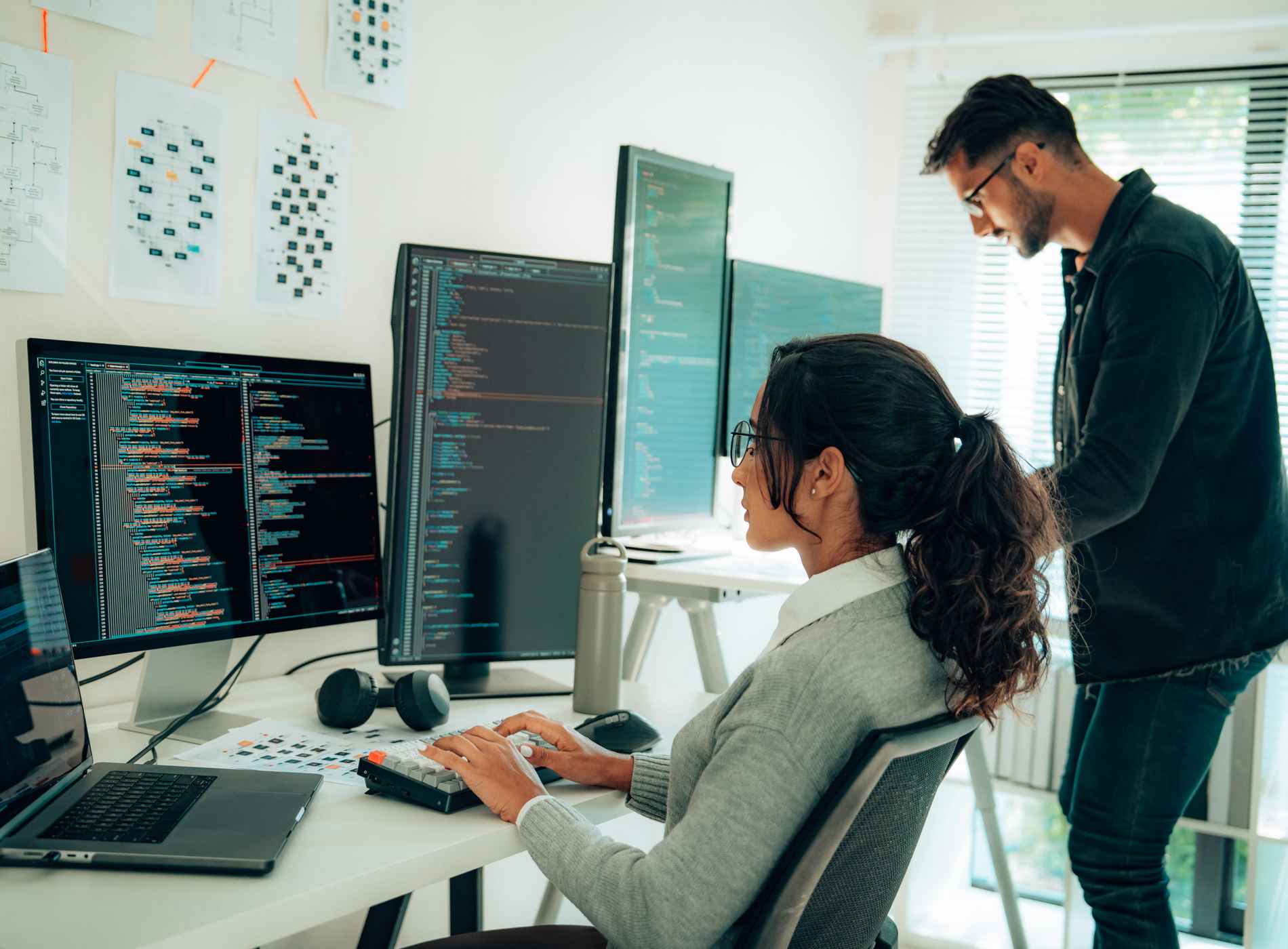 Two Hispanic Programmers Collaborating in Modern Office