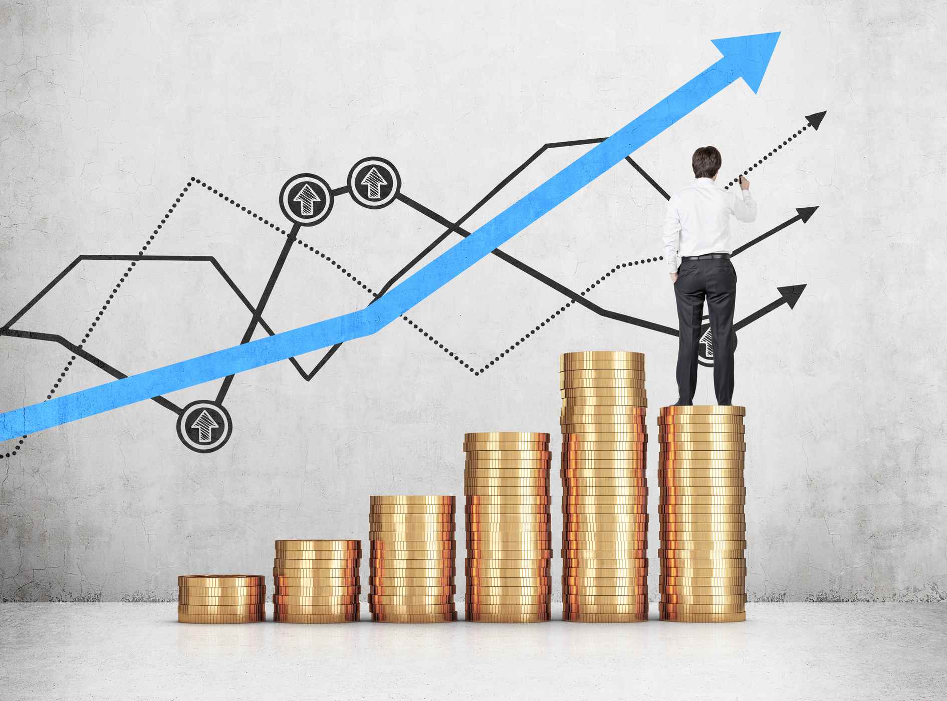 businessman standing on coins and draws a graph