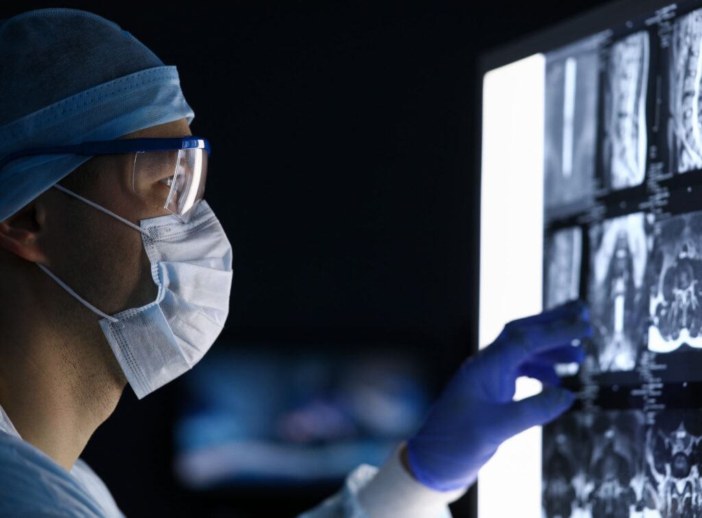 Male doctor in surgical clothes looking at vertebral mri scan headshot