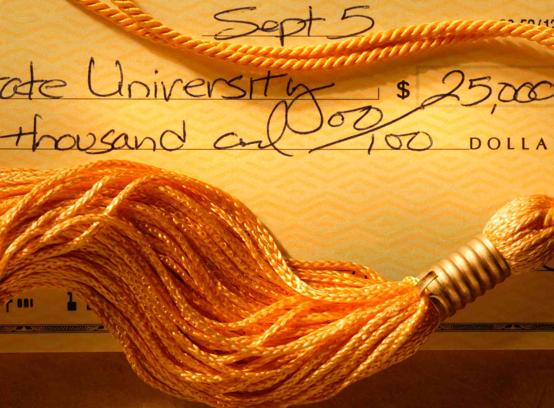 Closeup of checkbook and graduation tassel representing the soaring costs of a college education.Please see some similar pictures from my portfolio: