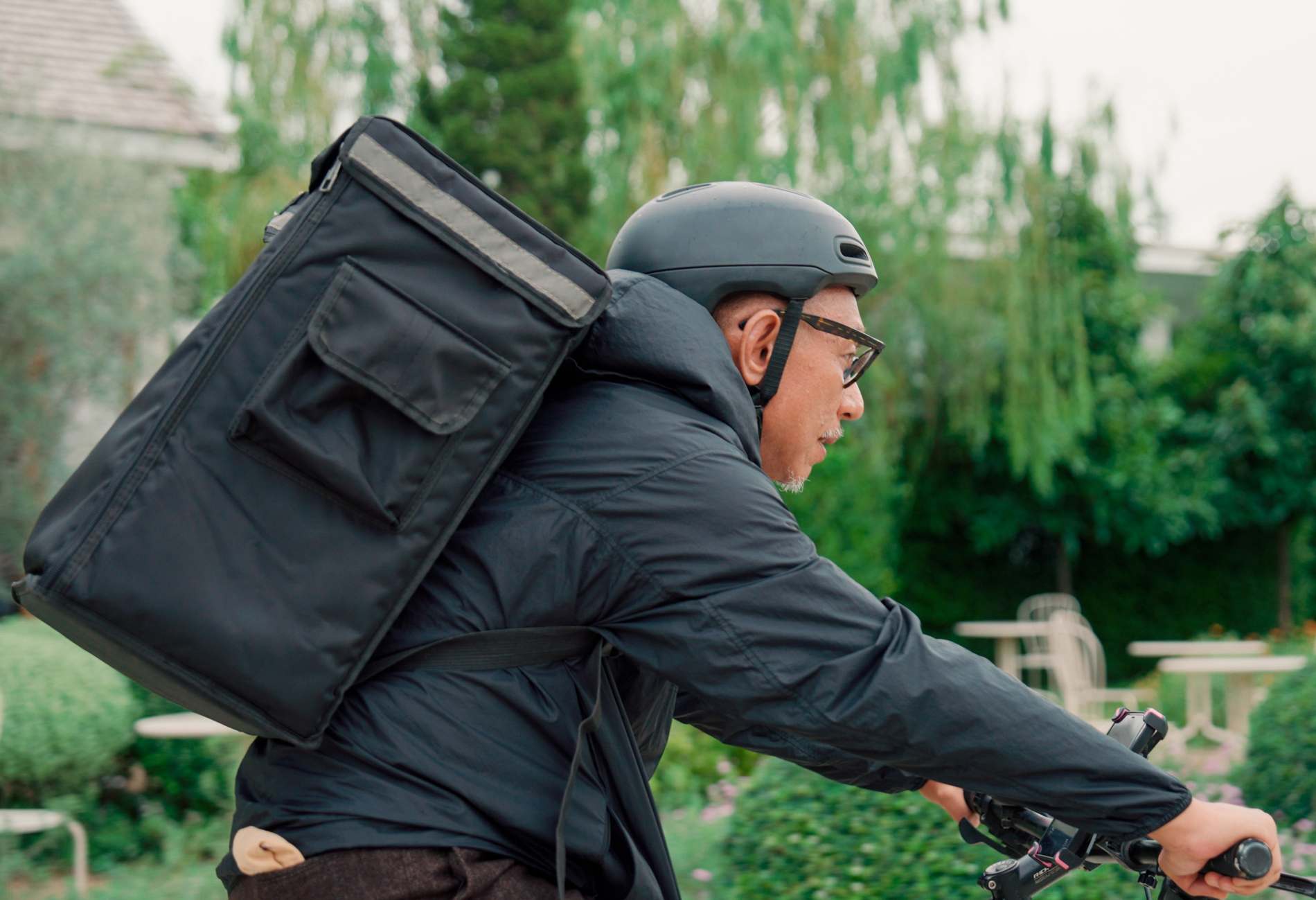 Delivery senior man working Backpack Rides a Bike on the Road To Deliver Orders for Clients and Customers.