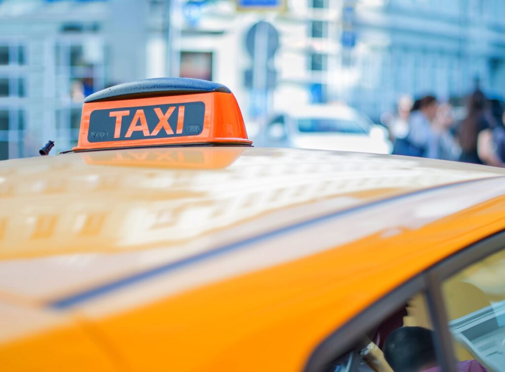 Checker taxi on the roof of a yellow car in the center of a big city