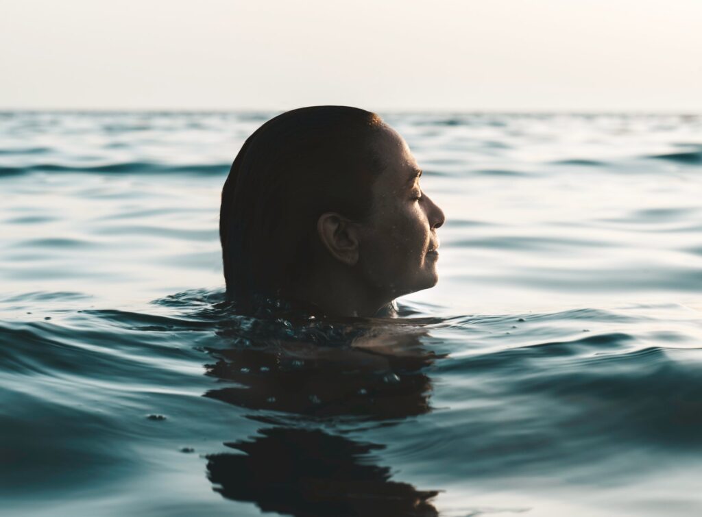 Side view of caucasian woman with long hair in sea at sundown